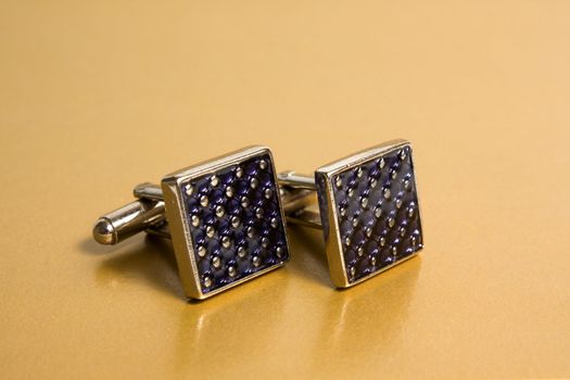 stainless steel cufflinks on the gold background