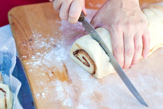 Woman hands cutting dough for Cinnamon Rolls 