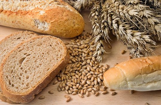 Various bakery products on wood with wheat ears and grain