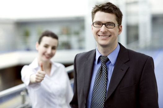 Business portrait - young handsom man with thumbs up sign in backgroud