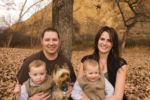 family with twin boys and pet dog at a park in Autumn