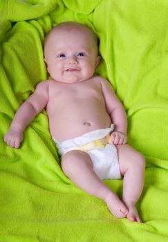 A smiling newborn baby on a green towel. 