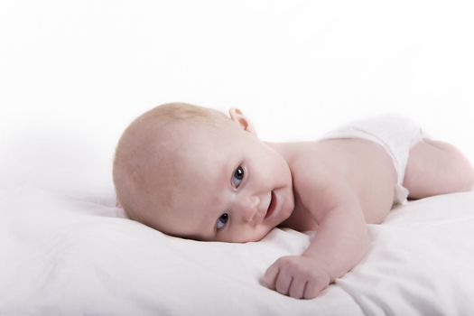 A smiling newborn baby on a white sheet. 