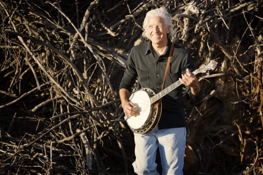 Banjo player with his instrument in front of a pile of sticks