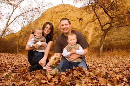 family with twin boys and pet dog at a park in Autumn