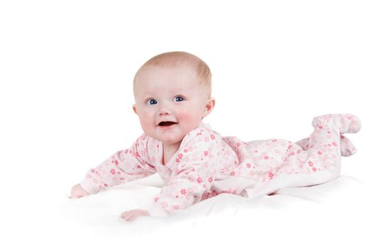 A smiling  baby girl on a white sheet in Pajamas. 