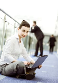 Businesswoman is sitting on the floor with notebook on her lap