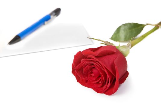 Red rose with envelope and pen in background