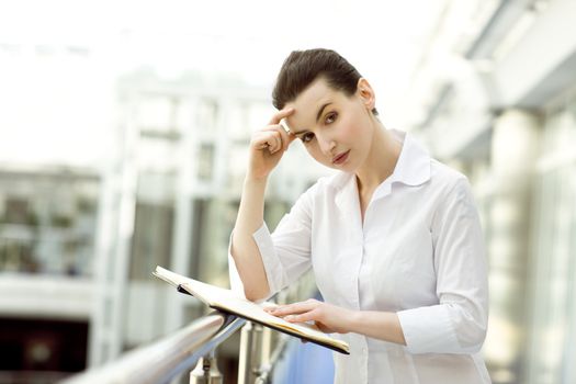 Portrait of young woman standing with business diary