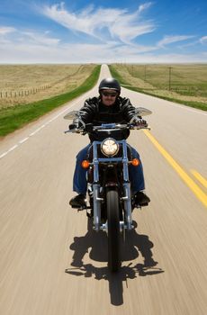 A biker taking a ride on a long strait road