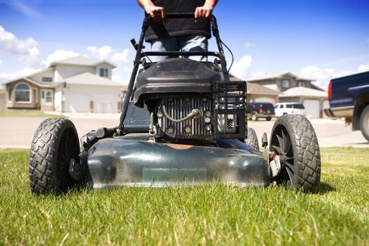 Close-up mowing the front lawn with houses in the background