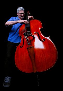 A musician playing a double bass low angle shot on a black background