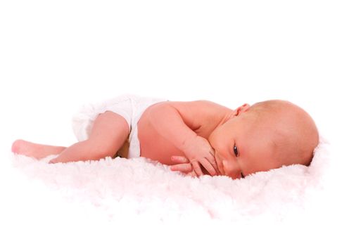 A newborn baby in diapers sucking on her fingers