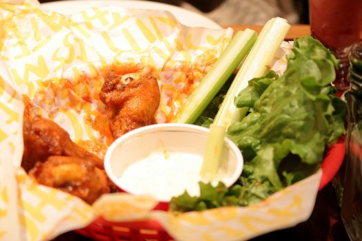 Chicken wings in a basket with ranch and celery