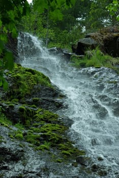 A small waterfall flowing down moss covered rocks.