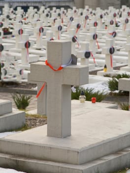 Winter cemetery with stone crosses and red ribbons