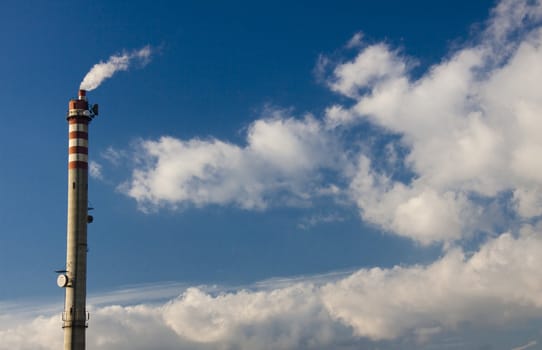 Blue sky white clouds and big industrial chimney.