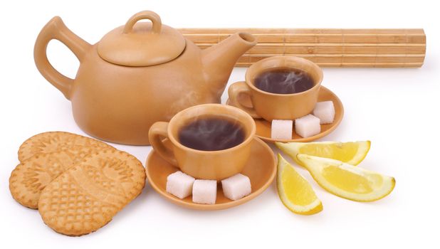 earthenware teapot, two cups of tea, lump shugar, sliced lemon and biscuits isolated on white background with clipping path              
