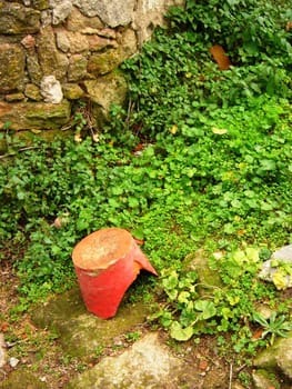 Old broken pot on green grass by old wall in spain willage.