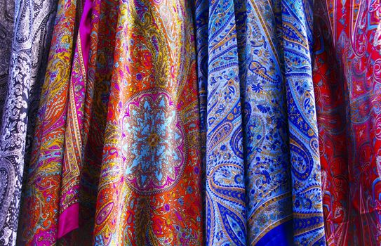 Closeup of the silk fabric of several hanging dresses