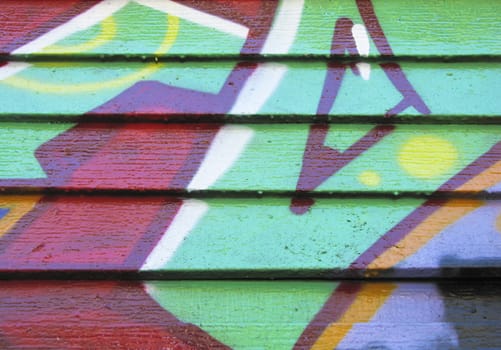 Red and green graffiti on wood slatted wall