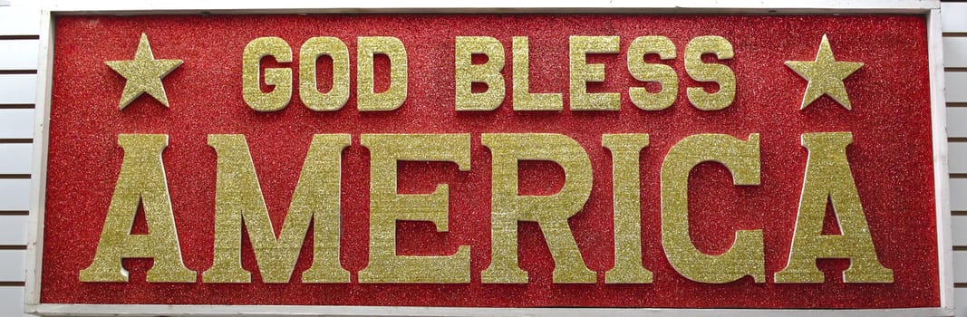 God Bless America sign written in gold glitter on a red glitter background