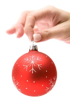 Female hand holding a red christmas bauble. Isolated on a white background.
