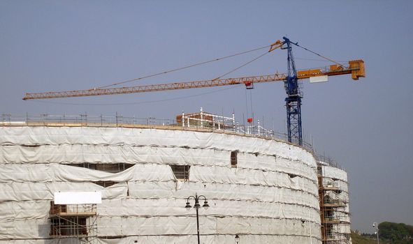 Overview of building site as construction taking place with crane.