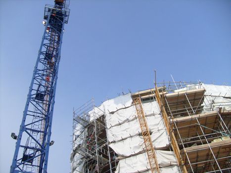 Overview of building site as construction taking place with crane.