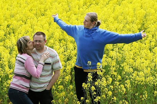 Happy middle-aged couple and their son in flower meadow.