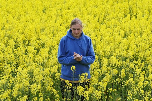 Happy young man in the yellow flower meadow.