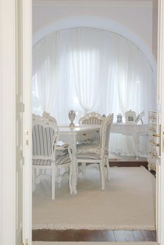 sunny classic interior with armchair and a chest of drawers against wide window
