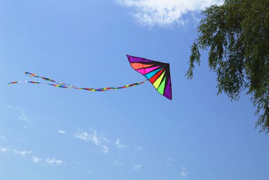 A beautiful and colorful kite in the blue sky with clouds