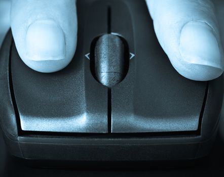 closeup of fingers on a computer mouse clicking,suggesting searching or informing, blue toned