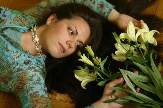 The girl lays on a floor, the sight is inverted to a bouquet from lilies
