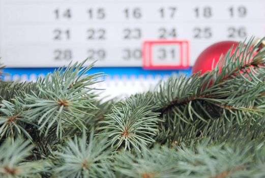 Fur-tree branches against a calendar and a New Year's toy removed close up