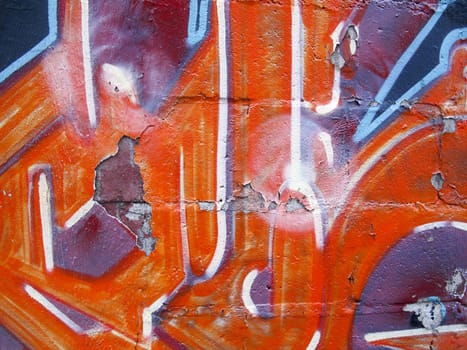 Old and peeling orange color graffiti on brick wall
