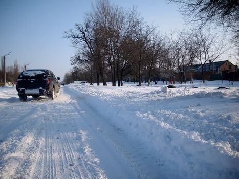 black station-wagon on the snow-bound road, winter