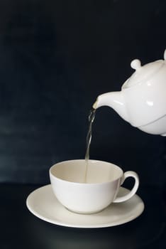 tea, pouring from a white china pot into a white china cup