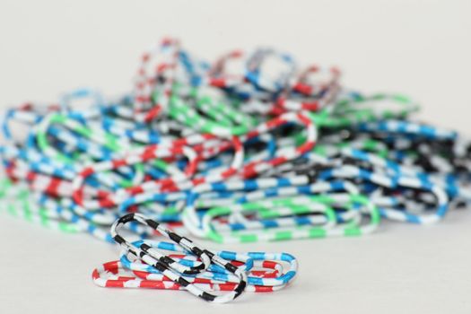 On a table paper clips are scattered. They of different colours. They bright.