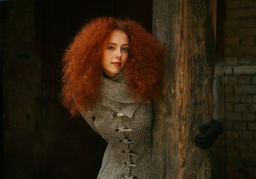 Portrait of the girl with red hair in a black coat