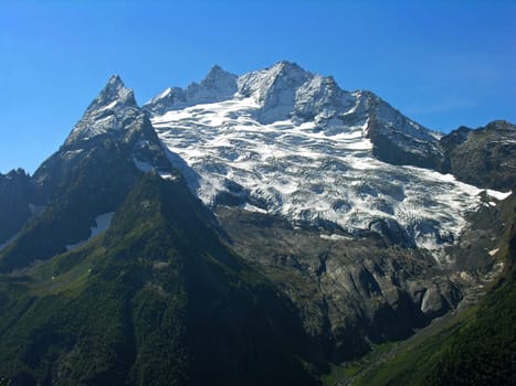 The mountain covered with a snow, is photographed on a background of the blue sky