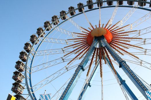Ferris wheel against bright blue sky on amusement park