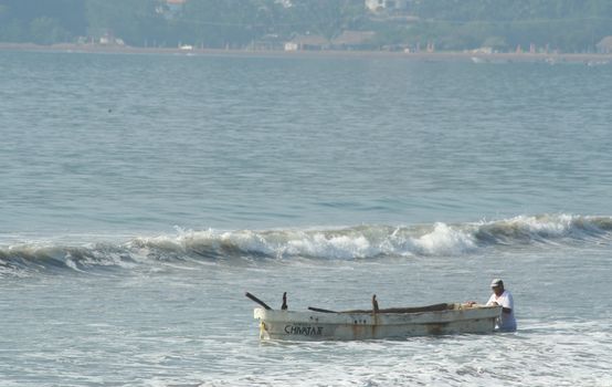 Fishermen with his boat fighting the waves