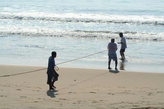 Fishermen pulling in a net from the beach