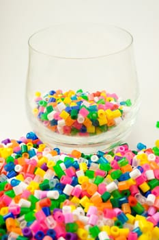 Bunch of colorful pearls for children in and around the glass.