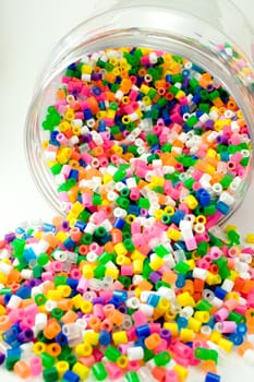 Bunch of colorful pearls for children in and around the glass.