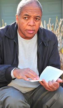 African american man reading a book outdoors.