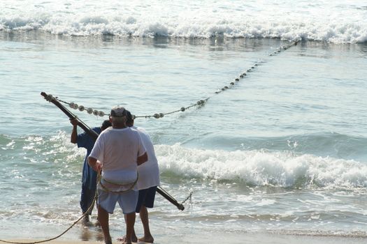 Fishermen pulling in net from the beach