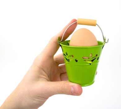 Hand holding green basket with egg, on white background.